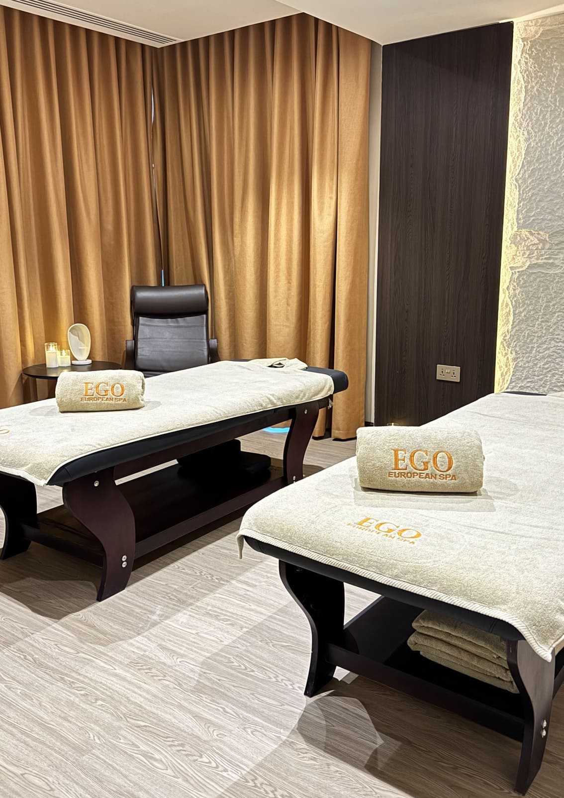 Couples massage suite at Ego European Spa Dubai — two parallel massage tables with EGO European Spa branded towels, private treatment room