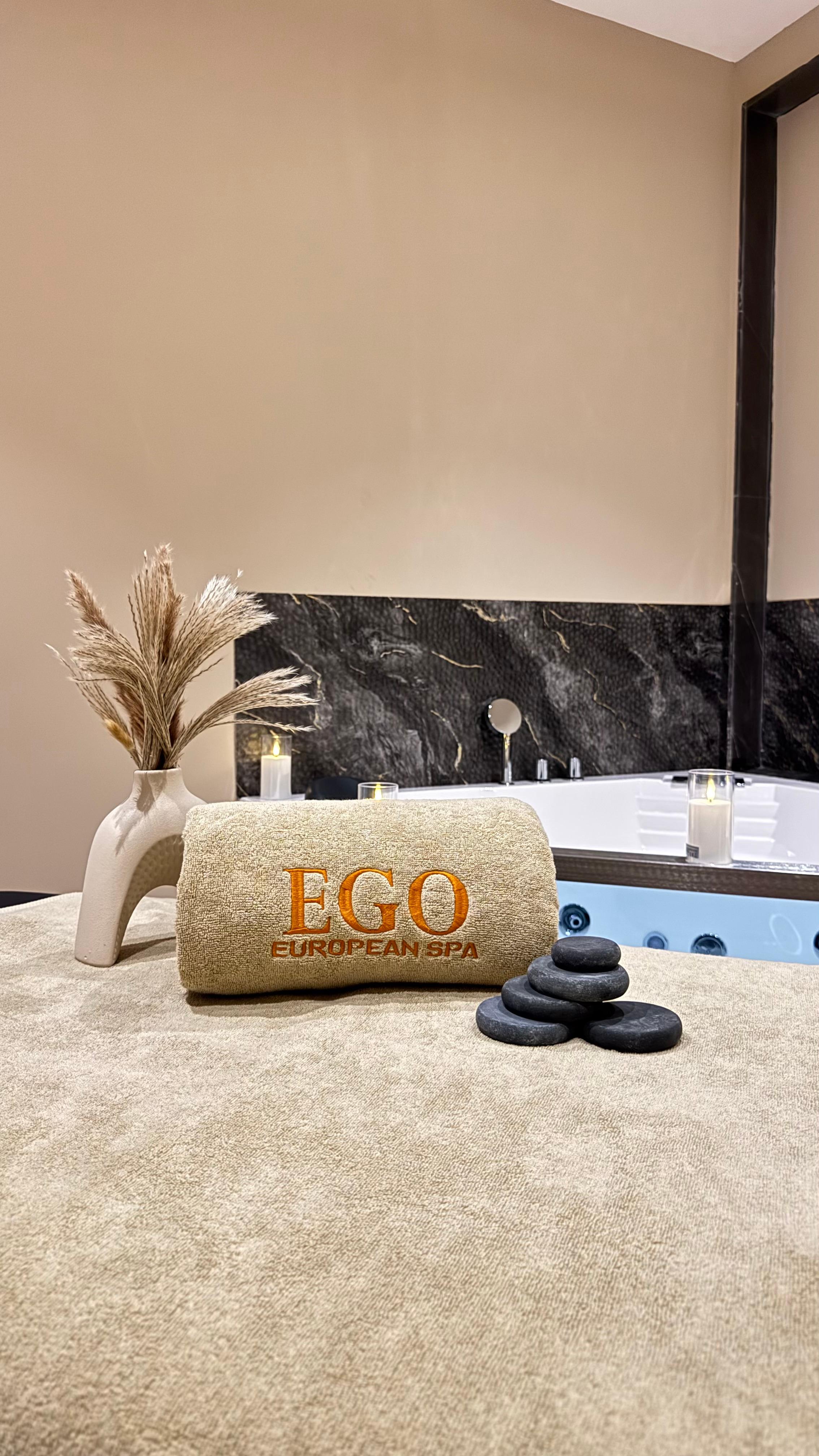 Treatment room at Ego European Spa Dubai with EGO branded towel, hot stones, and jacuzzi at Edge Creekside Hotel Deira